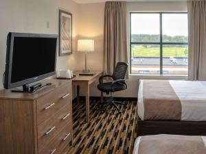 a hotel room with a bed and a desk with a television at Quality Suites Lake Wright Norfolk Airport in Virginia Beach