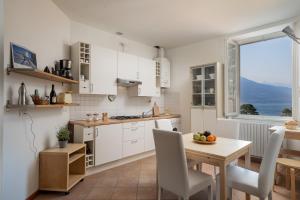 a kitchen with white cabinets and a table and chairs at Casa Sole in Varenna