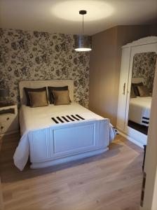 Schlafzimmer mit einem weißen Bett und einem Spiegel in der Unterkunft La maison du meunier in Autigny-la-Tour