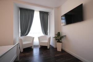 ティミショアラにあるPerla Sudului - Residenceのベッドルーム1室(椅子2脚、テレビ、窓付)