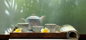 庫斯哈爾納加爾的住宿－庫格阿曼瓦納spa度假村，盘子,盘子上装有杯子,茶壶和鲜花