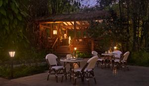 a group of tables and chairs in a garden at night at Amanvana Spa Resort, Coorg in Kushālnagar