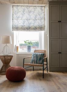 a living room with a chair and a window at Heritage Cottages Dundrum in Dundrum