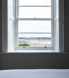 a window in a bedroom with a view of the ocean at Heritage Cottages Dundrum in Dundrum