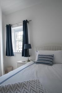 a bedroom with a bed with blue curtains and a window at Heritage Cottages Dundrum in Dundrum