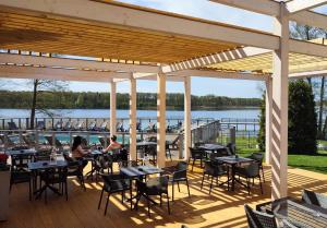 a deck with tables and chairs and a view of a lake at Hotel Tanzanit in Jesionka