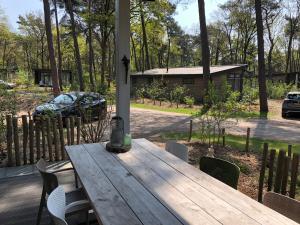 a wooden table with chairs and a house in the background at Natuurhuisje Pine & Oak 6 persoons in Hardenberg