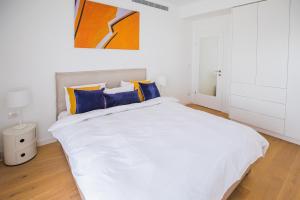 a bedroom with a white bed with blue and yellow pillows at The Haneviim Court - 3BDR High Standard in Jerusalem