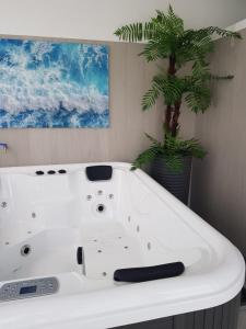 a white bath tub in a bathroom with a palm tree at Magilù Case con Jacuzzi in Castellammare del Golfo