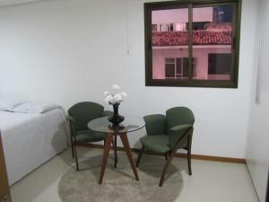 a bedroom with a table and two chairs and a bed at Moderno apartamento perto da praia in Maceió