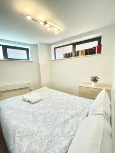 a bedroom with a white bed and two windows at Two bedrooms flat - Manchester city centre in Manchester