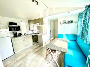 a small kitchen with a table and a blue wall at Spacieux Mobilhome Premium/Camping 5* in Vendays-Montalivet