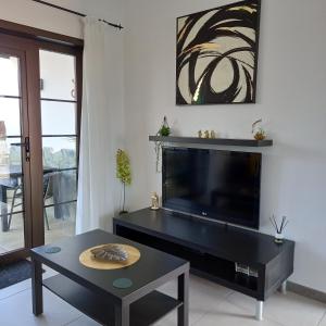 ein Wohnzimmer mit einem großen TV und einem Tisch in der Unterkunft Caleta Holiday Bungalow in Caleta de Fuste