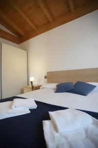 1 Schlafzimmer mit 2 Betten mit weißer Bettwäsche und blauen Kissen in der Unterkunft Apartments Camping Italia' 90 in Domaso