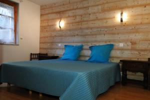 a bedroom with a blue bed with a wooden wall at Gîte 1804 Montagnes du Jura avec Spa et Sauna classé 3 étoiles in Foncine-le-Haut