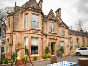 uma casa velha com uma mesa de pingue-pongue à frente. em The Meadowpark Bar, Kitchen & Rooms em Stirling