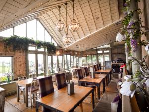 un restaurant avec des tables et des chaises en bois ainsi que des fenêtres dans l'établissement The Meadowpark Bar, Kitchen & Rooms, à Stirling