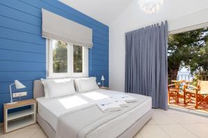 a bedroom with a large bed with a blue wall at PineReef Blue in Skala Rachoniou