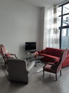 a living room with a red couch and chairs at Le jardin de l'horloge in La Rochelle