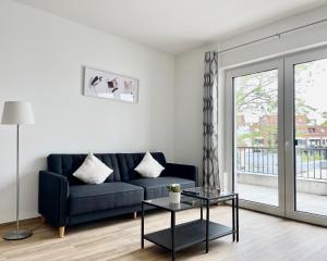 ein Wohnzimmer mit einem blauen Sofa und einem Glastisch in der Unterkunft Schöne Apartments in der Innenstadt von Osnabrück I home2share in Osnabrück