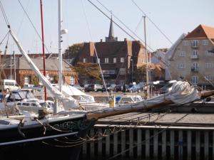 una barca a vela ormeggiata in un porto turistico con edifici di Det Gamle Hotel Rudkøbing a Rudkøbing
