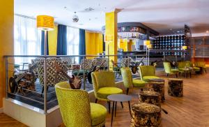 a bar with yellow and green chairs and tables at mightyTwice Hotel Dresden in Dresden