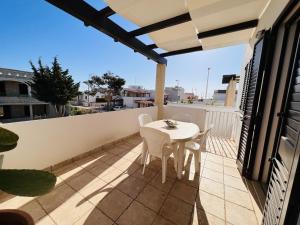 un patio con tavolo e sedie bianchi sul balcone. di Casa Carolina a Torre Pali