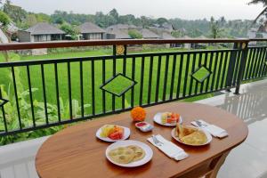 einen Holztisch mit Tellern aus Essen auf dem Balkon in der Unterkunft Mira Family Cottages in Ubud