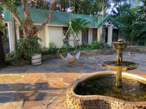 a fountain in front of a house with a statue at Waterloo Guest House in Durban