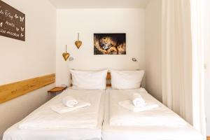two beds in a room with white sheets and towels at Fischener Biberle in Fischen +1 photo