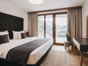 a bedroom with a large bed with a desk and a window at VAYA St Anton in Sankt Anton am Arlberg