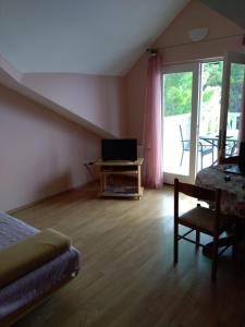 Un dormitorio con una cama y un escritorio con televisión. en Apartments Elvira, en Sveta Nedelja