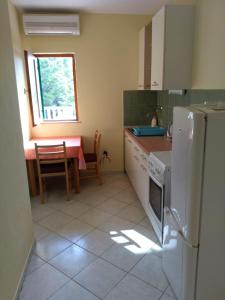Una cocina con una mesa y un refrigerador blanco. en Apartments Elvira, en Sveta Nedelja