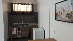 a kitchen with a stove and a white refrigerator at STUDIO CENTRAL IV in Cascavel