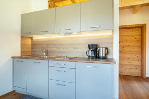 una cucina con mobili bianchi e un lavandino di Mayrhof Apartment Im Kirschgarten a San Pancrazio dʼUltimo Altre 12 foto