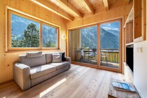 un soggiorno con divano e ampie finestre di Mayrhof Apartment Im Kirschgarten a San Pancrazio dʼUltimo