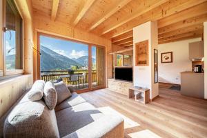 un soggiorno con un divano e una grande finestra di Mayrhof Apartment Im Kirschgarten a San Pancrazio dʼUltimo