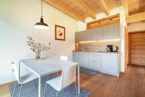 una cucina e una sala da pranzo con tavolo e sedie bianchi di Mayrhof Apartment Im Kirschgarten a San Pancrazio dʼUltimo