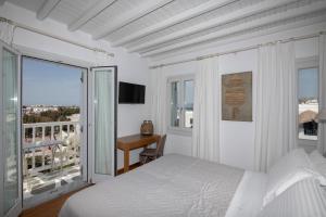 a white bedroom with a bed and a balcony at Elena Hotel Mykonos in Mikonos