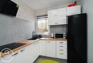a kitchen with white cabinets and a black refrigerator at Domki Na Klinie in Średnia Wieś