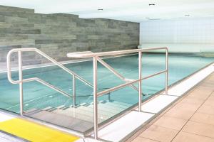 a swimming pool with a metal railing next to the water at Alpenblume in Fischen
