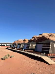 a row of buildings in the desert with a mountain at Discover the life of Wadi Rum camp in Wadi Rum