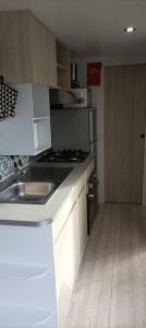 a kitchen with a sink and a stove top oven at "Mar e sou" 412 Camping La Réserve SIBLU in Gastes