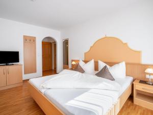 a bedroom with a large bed with white sheets and a television at Apartment Rosa-6 by Interhome in Mayrhofen +21 photos
