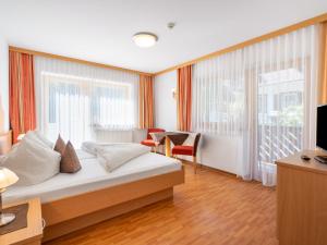 a hotel room with a bed and a desk and windows at Apartment Rosa-6 by Interhome in Mayrhofen