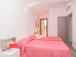 two beds in a white room with pink sheets at Holiday Home Case Greche Nuove Villetta 2 - REI239 by Interhome in Costa Rei