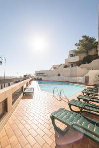 uma piscina com espreguiçadeiras verdes ao lado de um edifício em Residence Pierre & Vacances Les Balcons de Collioure em Collioure
