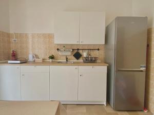 cocina con armarios blancos y nevera de acero inoxidable en Guest House Service - Game Apartment, en Modugno