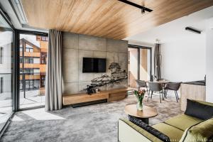 ein Wohnzimmer mit einem Sofa und einem Fernseher an der Wand in der Unterkunft Tremonti Hotel Karpacz in Karpacz