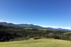 a view of a green field with mountains in the background at Hillandale Hideaway in Plettenberg Bay
